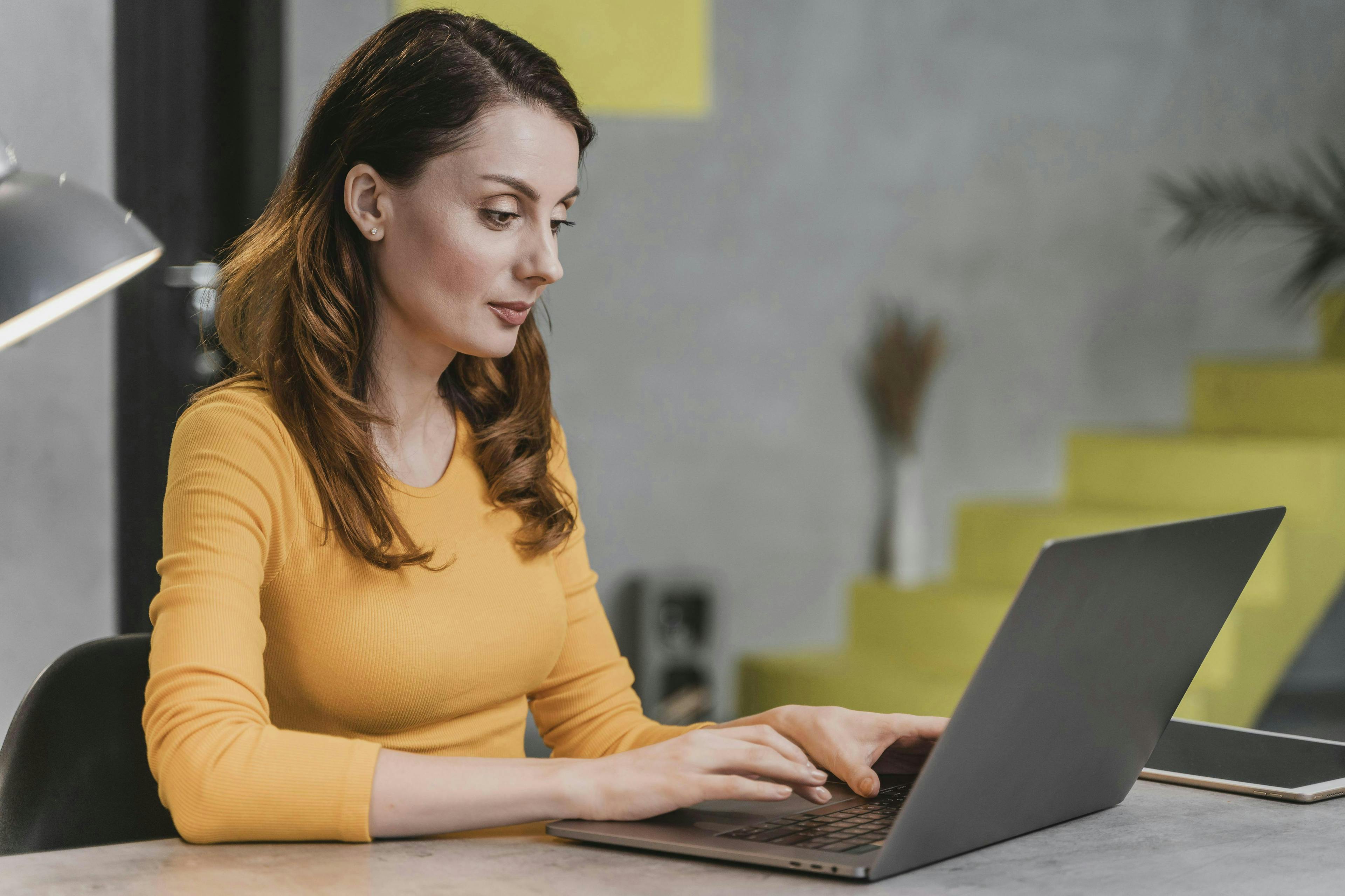 A side view of a woman using a laptop