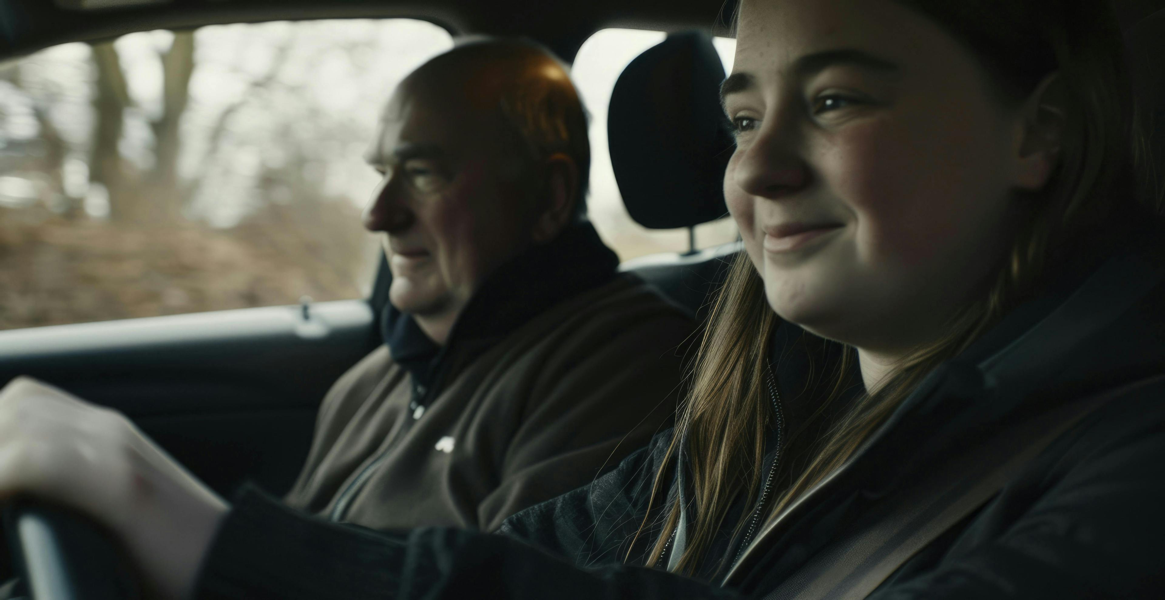 A young woman having a driving lesson with a middle-aged man